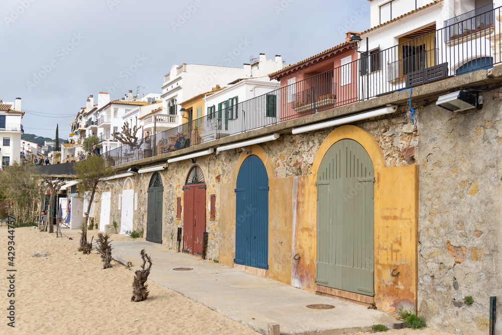 View of colored doors of fishermen's huts in front of the sand of the beach in CALELLA DE PALAFRUGELL