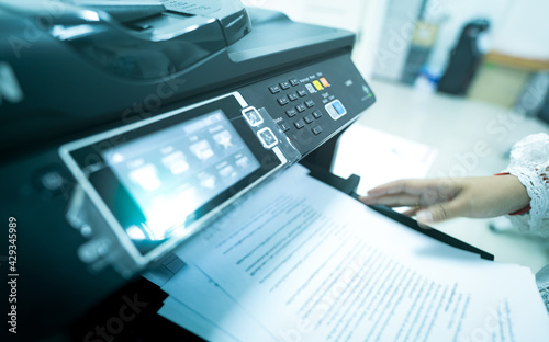 Office worker print paper on multifunction laser printer. Copy, print, scan, and fax machine in office. Modern print technology.  Photocopy machine. Document and paper work. Scanner. Secretary work. photo