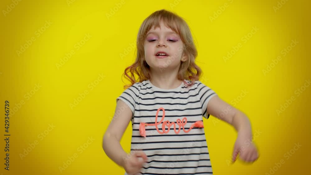 You and me here and right now. We are team. Little child girl looking authoritative, fingers down, demanding immediate serious conversation, giving command. Kid children on yellow studio background