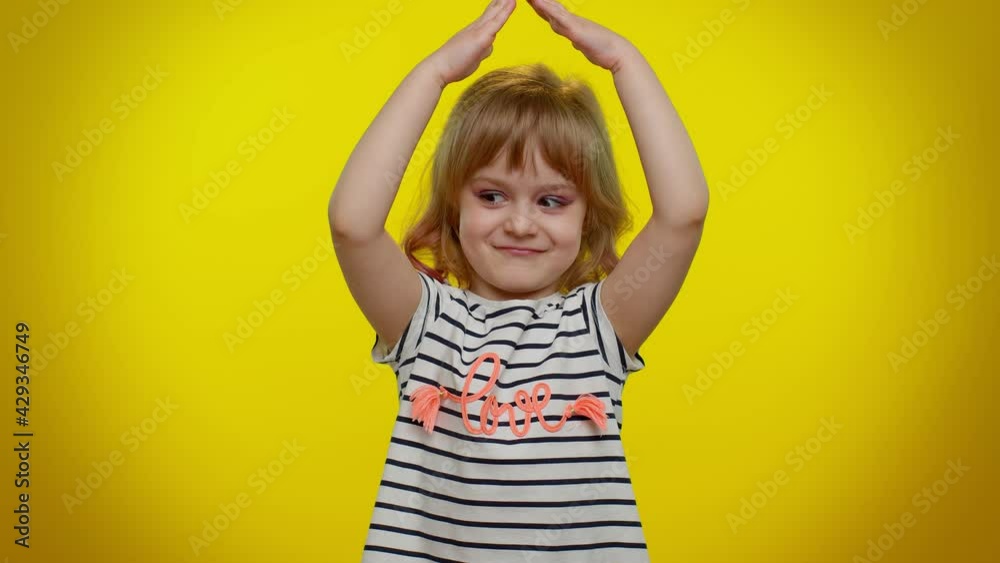 Blonde teen child kid girl playing childish catching up game, feeling in safe making roof above head with hands, insurance, security service. Childhood. Young children on yellow studio background Blonde teen child kid girl playing childish catching up game, feeling in safe making roof above head with hands, insurance, security service. Childhood. Young children on yellow studio background