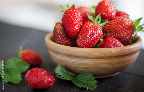 Fresh strawberries in a clay bowl on a wooden table