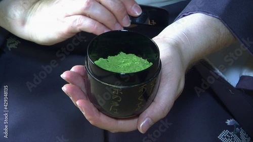 The cap of a chazutsu tea canister is removed to show the green Matcha tea inside. photo