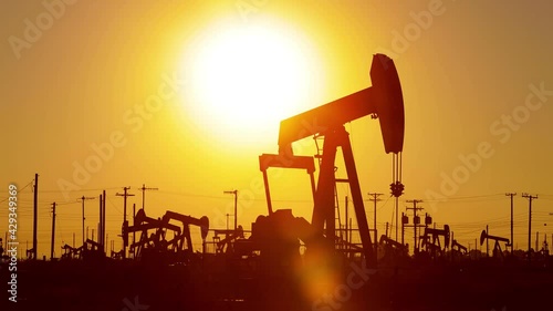 The sun rises behind oil pumps in California