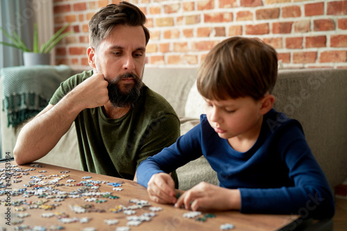 Son with father solving jigsaw puzzle in the living room