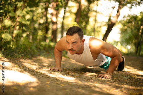 Man working push-ups in the forest. © liderina