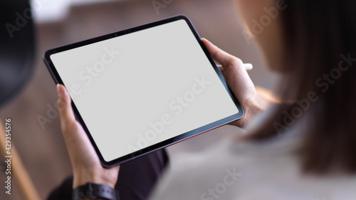 Over shoulder close up view of businesswoman using digital tablet with mock up screen