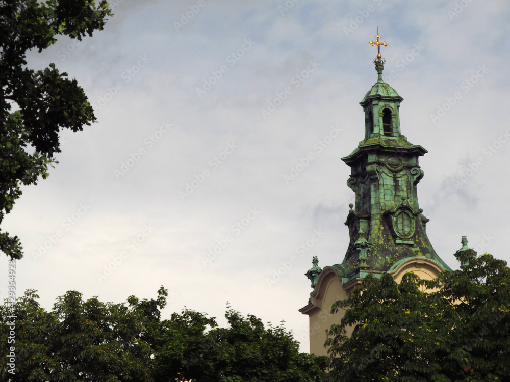Widok na wieżę katedry Wniebowzięcia Najświętszej Maryi Panny we Lwowie na tle liści, Ukraina