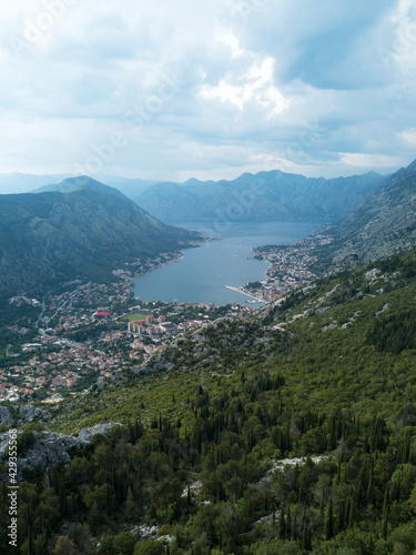 Aerial view. Bay of Kotor, Dalmatia, Montenegro. Top view of mountains, sea, clouds, forest, cypress trees, rocks, winding road. Summer landscape. Balkans. Drone.
