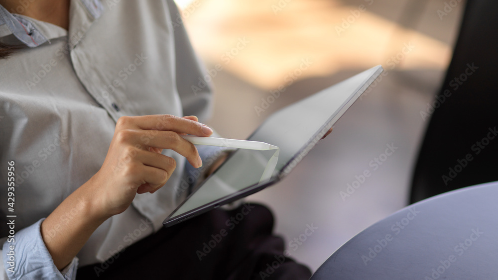 Close up view of young female using mock up blank screen digital tablet in office room