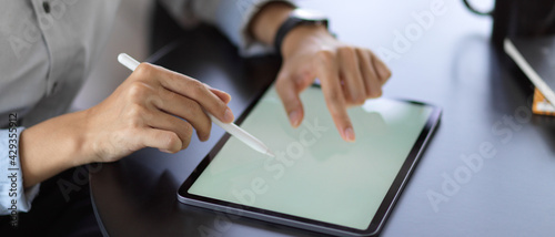 Female using mock up blank screen digital tablet while working on her project