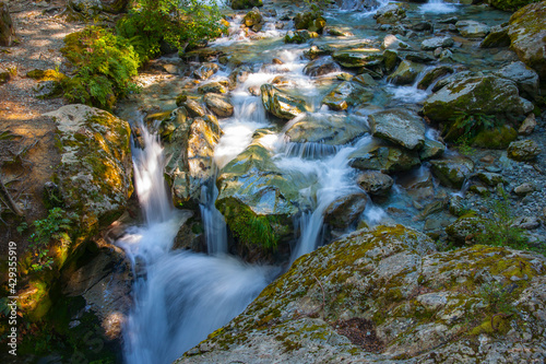 Shallow river water splashing and falling over rocky riverbed photo