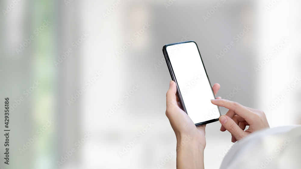 Cropped shot of woman holding mock up smartphone with blurred office background