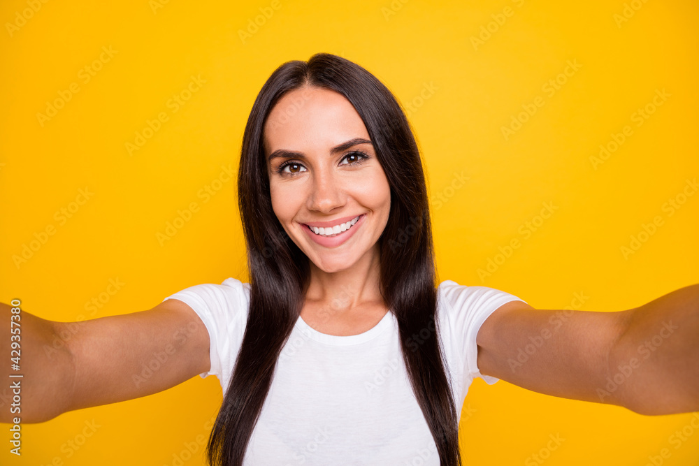 Photo portrait of female influencer taking selfie on camera smiling isolated on vivid yellow color background Photo portrait of female influencer taking selfie on camera smiling isolated on vivid yellow color background