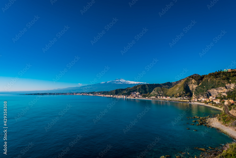 Bright sunny day at Giardini Naxos bay, Mt. Etna in the distance. Tranquil seascape 