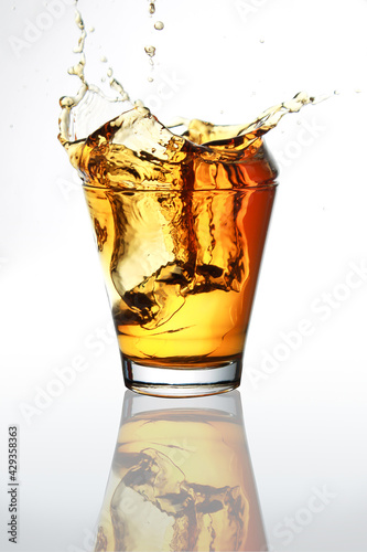 Ice cubes splashed into a whiskey glass