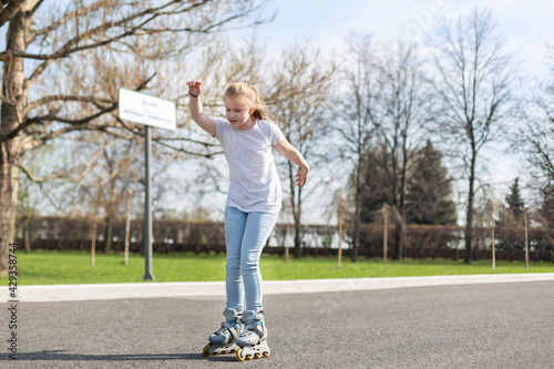 A teenage girl quickly rides on roller skates, raising her hand to maintain balance. Active recreation concept