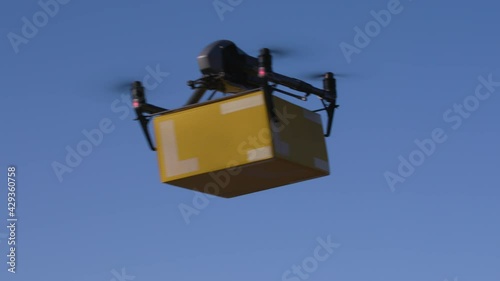 delivery drone carrying parcel flying across the blue sky
