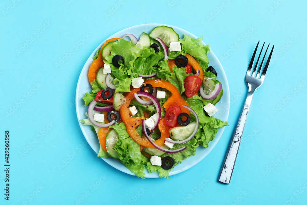 Plate of greek salad and fork on blue background Plate of greek salad and fork on blue background