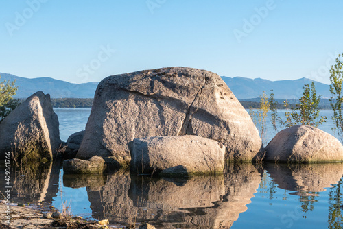 Set of large stones reflected in the water along the shore of the Valmayor reservoir