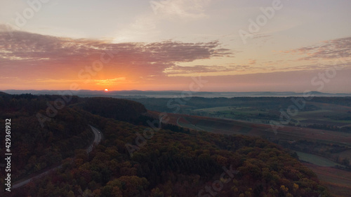 Eerie scenery of an empty highway in a forest at golden sunset photo