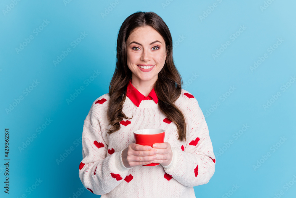 Photo of charming cute young woman dressed hearts print pullover holding red cup isolated blue color background Photo of charming cute young woman dressed hearts print pullover holding red cup isolated blue color background