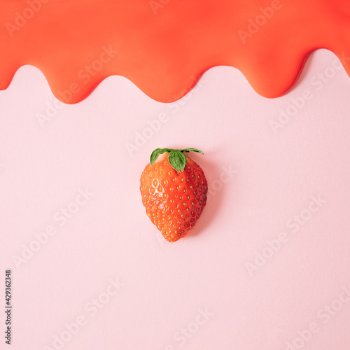 Fresh flat lay composition with single strawberry and red melting cream on pink background. photo