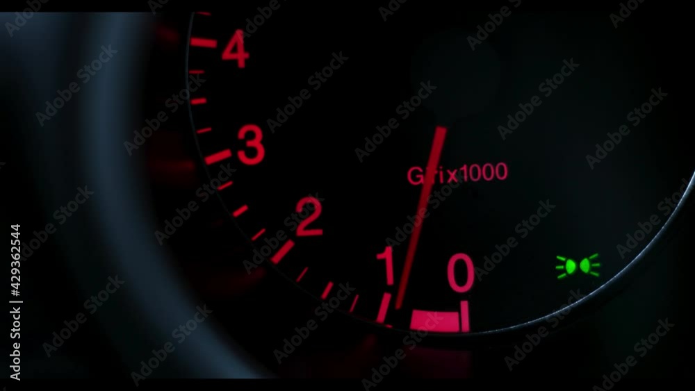 Car gauge tachometer rev counter showing engine revving up and idling
