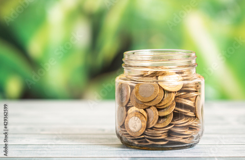 Coin in glass bottle with money stack