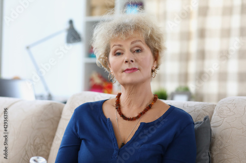 Portrait of elderly woman sitting on sofa at home