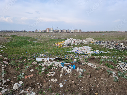 Piles of industrial and home waste lay on a field near inhabited blovks of flats. photo