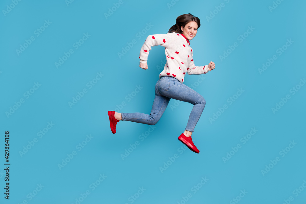 Full length photo of sweet young woman dressed hearts print pullover running jumping high isolated blue color background