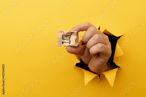 Hand with a small broken delivery box through a yellow paper hole
