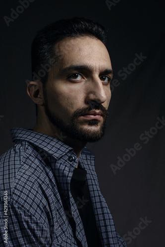 Male portrait on a gray background. A man with a beard. Men's style. Natural male portrait. Man in a blue shirt