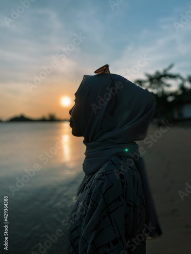 Medium Shot Woman in front of Sunset at Beautiful Beach