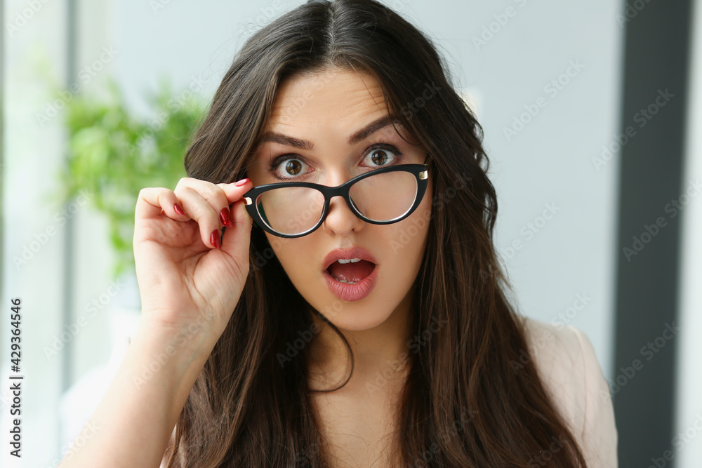 Young surprised woman adjusting glasses for vision Young surprised woman adjusting glasses for vision