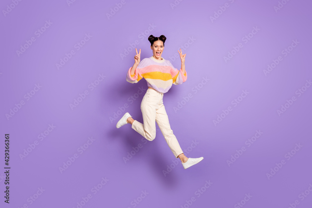 Full length photo of sweet charming young woman wear striped pullover jumping showing v-sign isolated purple color background