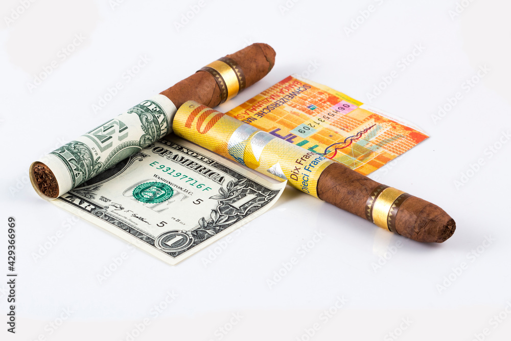 Cuban cigar on a rolled dollar and rolled euro on the white background stock photo