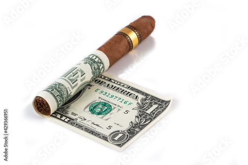 Cuban cigar on a rolled dollar on the white background stock photo