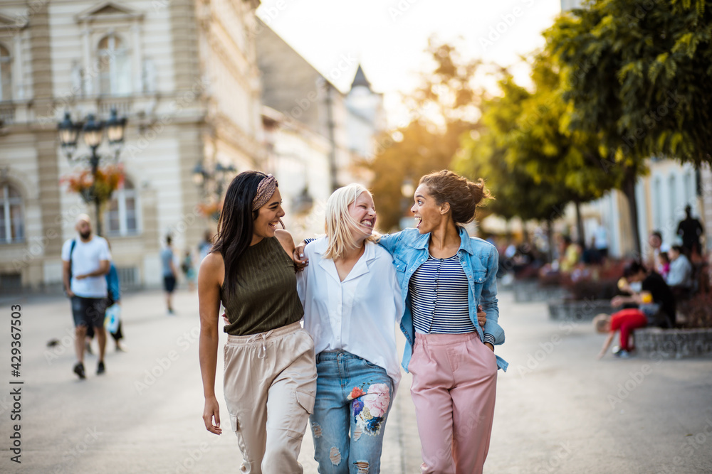 Three women walking trough street and talking.