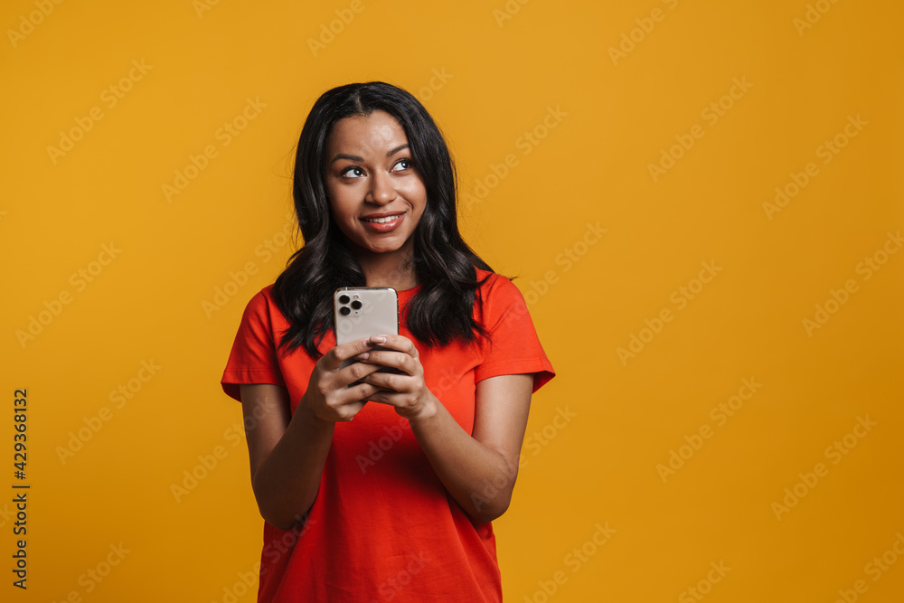Obraz premium Young black happy woman smiling and using mobile phone