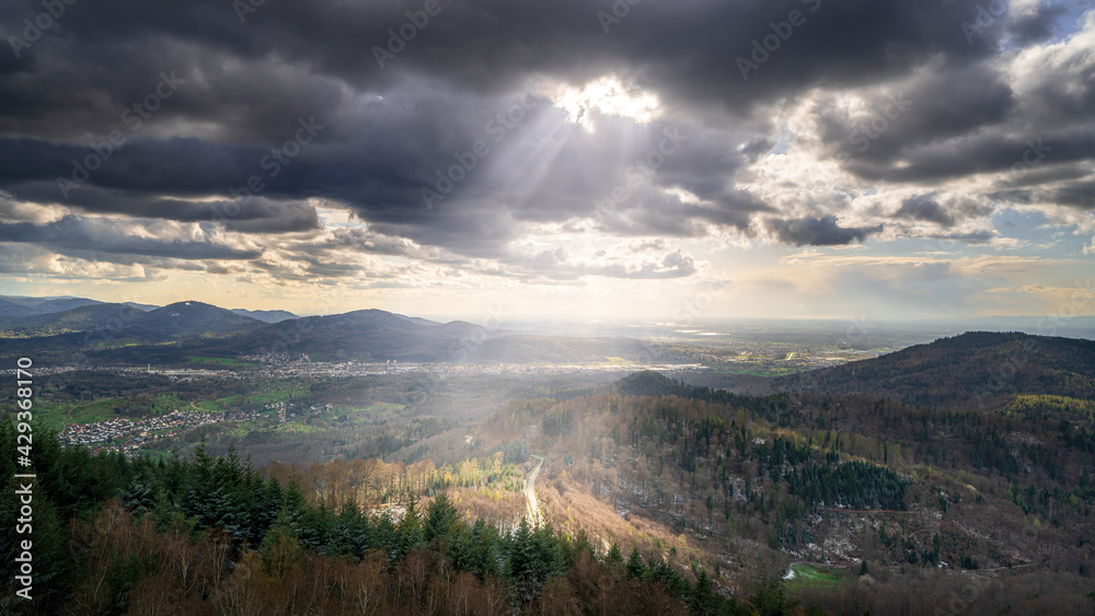 The sun shines through the clouds on a road in the black forest