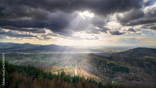 The sun shines through the clouds on a road in the black forest