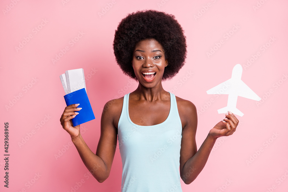 Portrait of impressed brunette curly lady hold tickets plane wear blue top isolated on pastel pink color background Portrait of impressed brunette curly lady hold tickets plane wear blue top isolated on pastel pink color background
