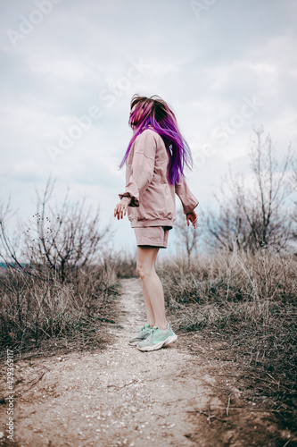 a girl with purple hair in a pink tracksuit runs on a mountain