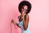 Photo of happy funky dark skin young woman hold sing mic music lover isolated on pink color background