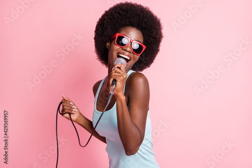 Photo of happy funky dark skin young woman hold sing mic music lover isolated on pink color background