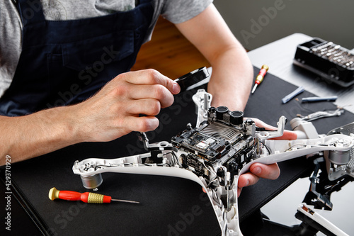 Close-up Of Person's Hand Repairing Drone Using Screwdriver. a man working in a repair shop