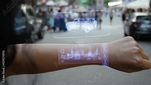 Female hand activates conceptual HUD holograms on smart bracelet with Bulletproof Suv. Unrecognizable woman with holographic technology on a city street background photo