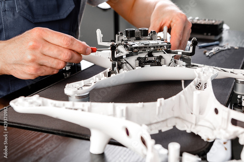 Close-up Of Person's Hand Repairing Drone Using Screwdriver. a man working in a repair shop