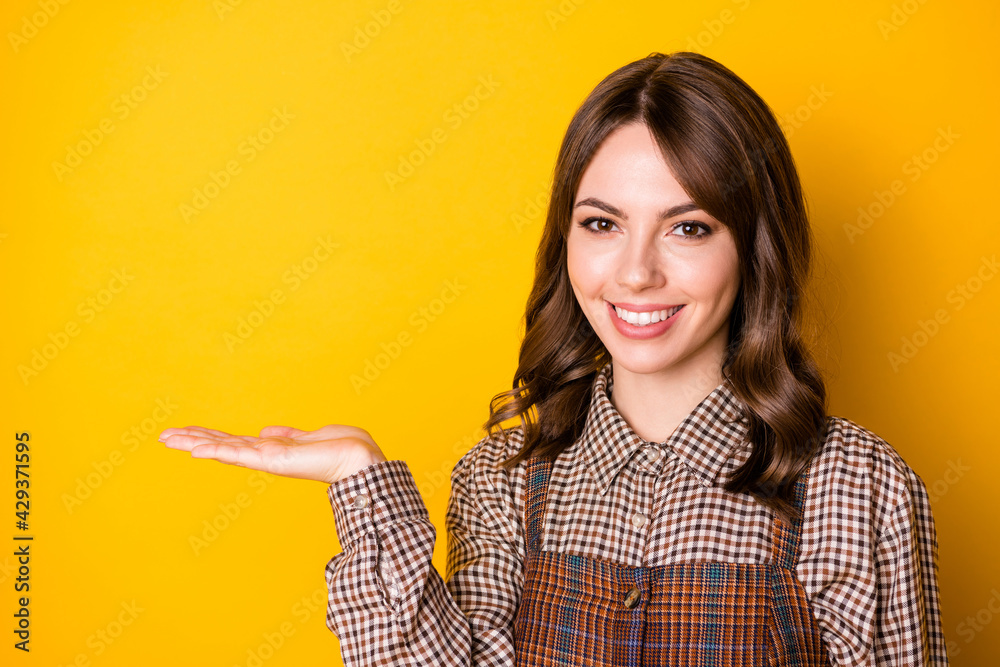 Photo of cheerful person toothy smile arm palm holding show product isolated on yellow color background Photo of cheerful person toothy smile arm palm holding show product isolated on yellow color background